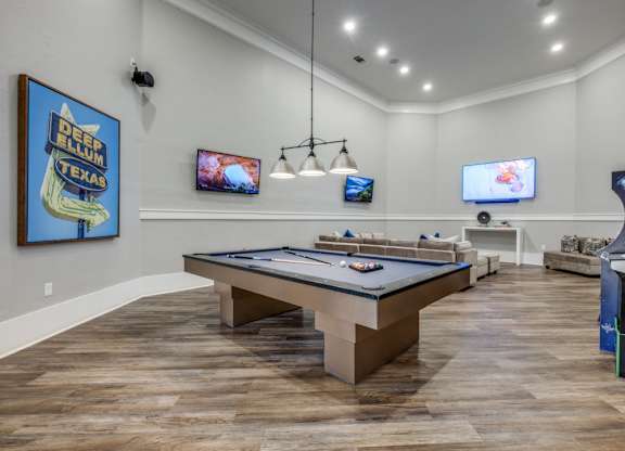 A room with a pool table and a TV mounted on the wall.