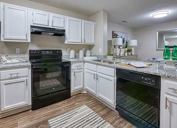 A kitchen with white cabinets and black appliances.