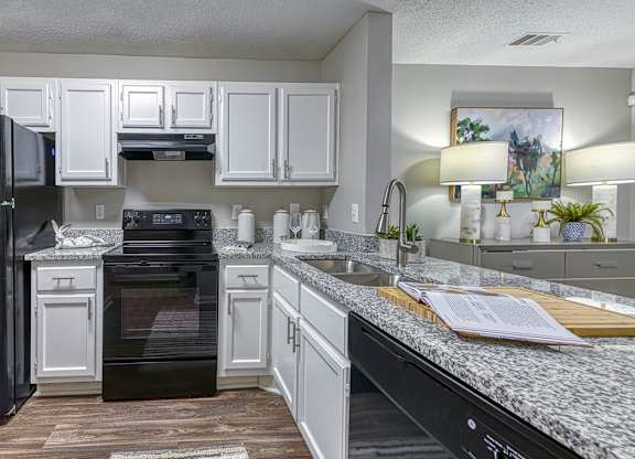 A kitchen with black appliances and white cabinets.