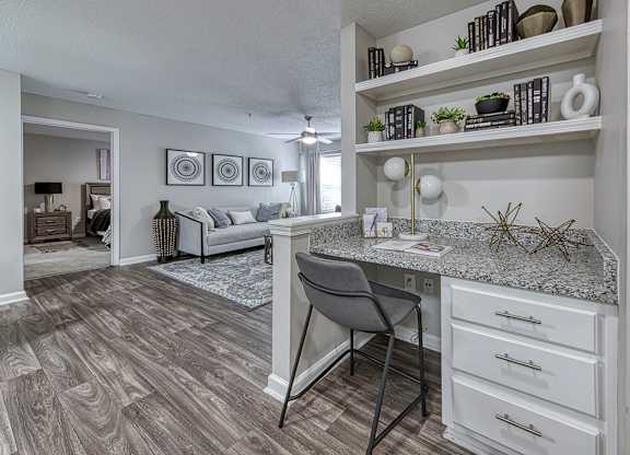 A kitchen with a desk and a chair in front of it.
