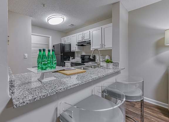 A kitchen with granite countertops and white cabinets.