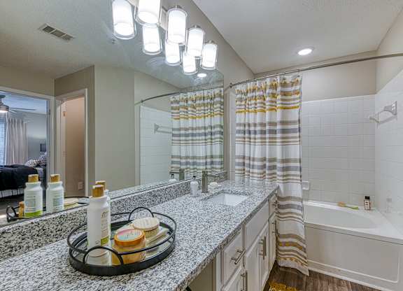 A bathroom with a white tub, sink, and shower curtain.