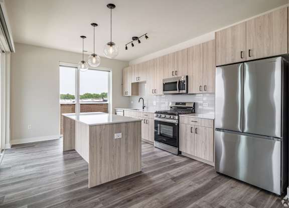 A modern kitchen with a large island and stainless steel appliances.