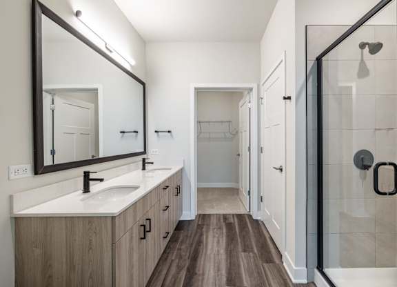 A bathroom with a sink, mirror, and shower.