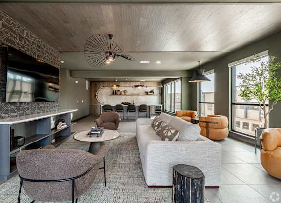 A modern living room with a grey sofa, a brown armchair, and a wooden ceiling.