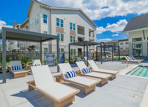 A poolside area with sun loungers and a building in the background.