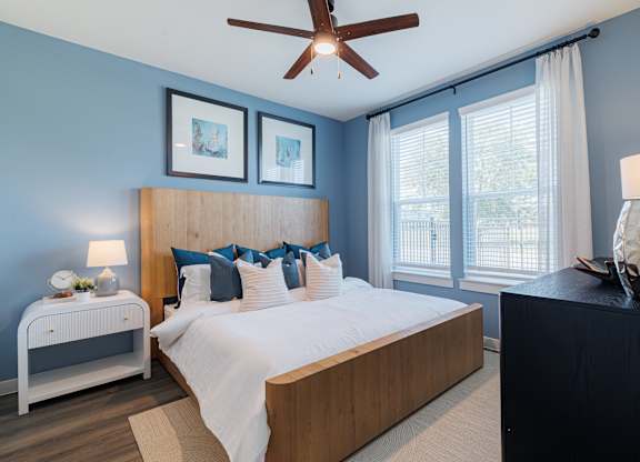 A bedroom with a bed, nightstand, and a ceiling fan.