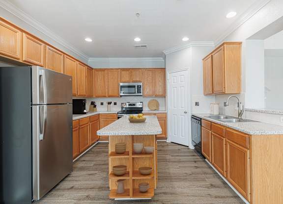 A kitchen with wooden cabinets and a stainless steel refrigerator.