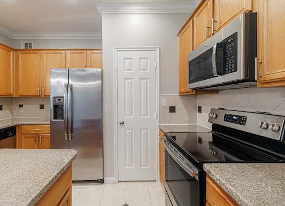 A kitchen with a refrigerator, microwave, and oven.