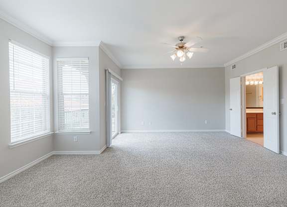 A spacious room with a ceiling fan and carpeted floor.