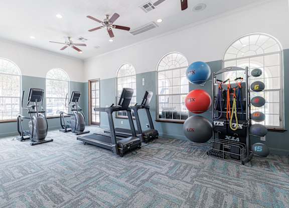 A gym with a variety of equipment including treadmills, elliptical machines, and weight racks.