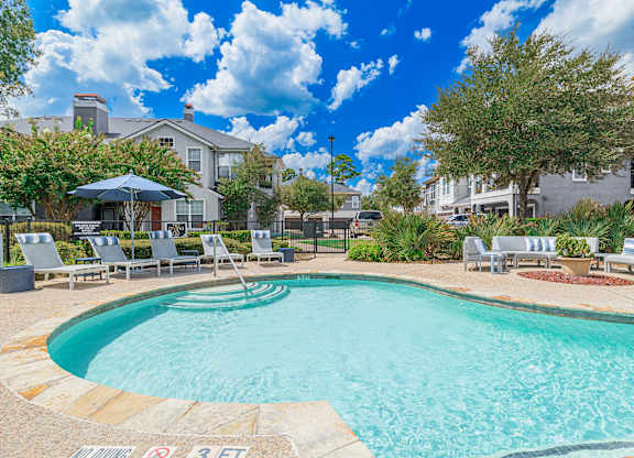 A swimming pool surrounded by lounge chairs and umbrellas.