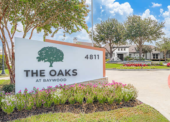 A sign for "The Oaks at Baywood" is displayed in front of a building.