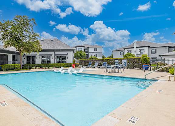 A swimming pool surrounded by lounge chairs and a clear blue sky.