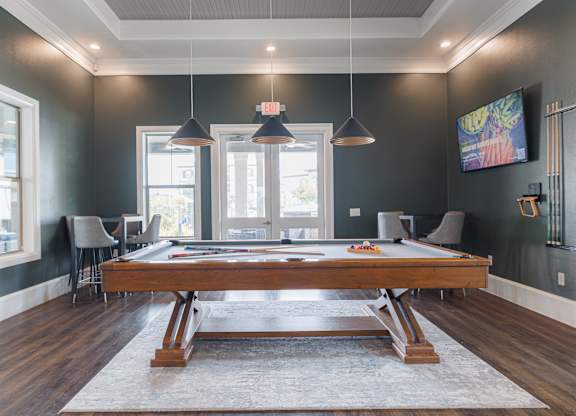 A room with a pool table and a television mounted on the wall.