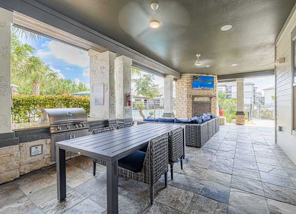 A patio with a table and chairs and a grill.