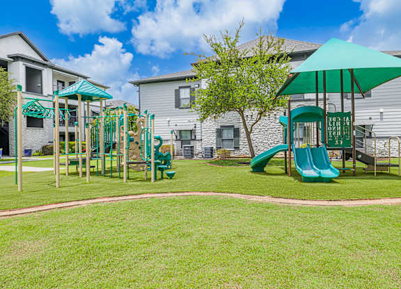 A playground with a green slide and a green umbrella.