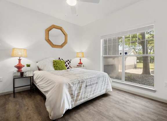 A bedroom with a bed, two lamps, and a mirror on the wall.