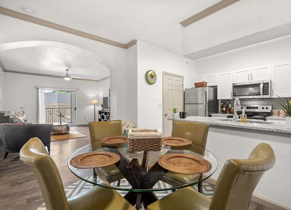 A modern dining room with a glass table and chairs.