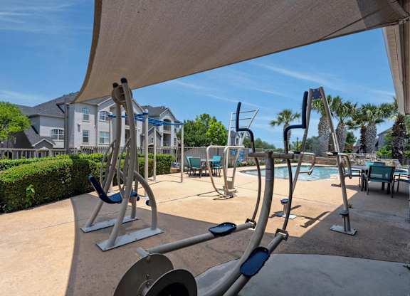 A gym with exercise equipment and a pool in the background.