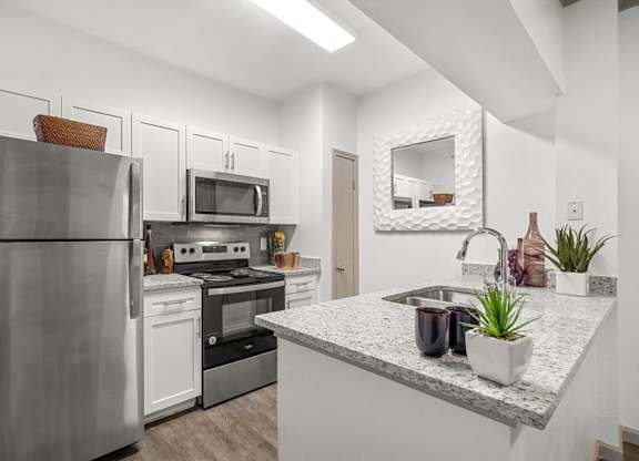 A modern kitchen with a stainless steel refrigerator, microwave, oven, and sink.
