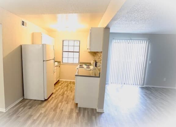 an empty kitchen with a refrigerator and a sink