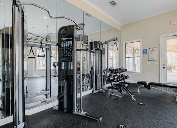 A gym with a variety of equipment including a squat rack, a leg press machine, and a bench press.