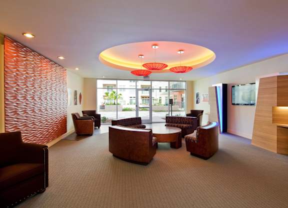 A modern lounge area with brown leather chairs and a carpeted floor.