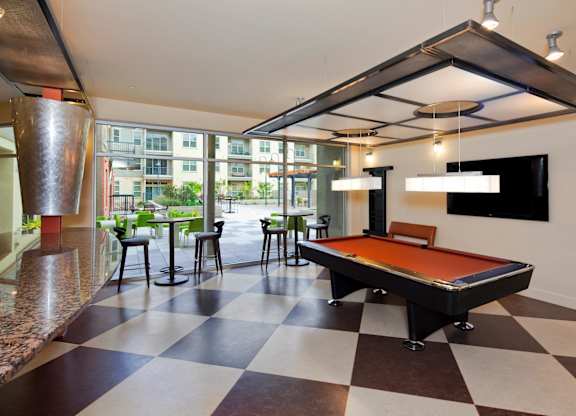 A pool table is in the middle of a room with a checkered floor.