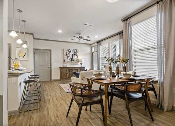A dining room with a table set for two and a kitchen area in the background.