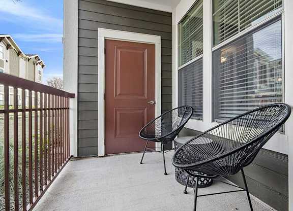 A black metal chair is placed on a concrete porch.