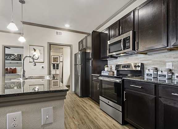A modern kitchen with black cabinets and stainless steel appliances.