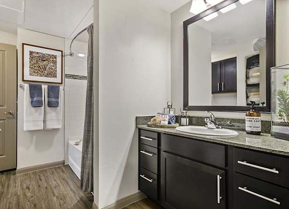 A bathroom with a sink, mirror, and a shower.