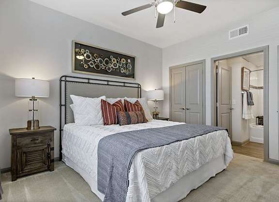 A bedroom with a large bed and a ceiling fan.