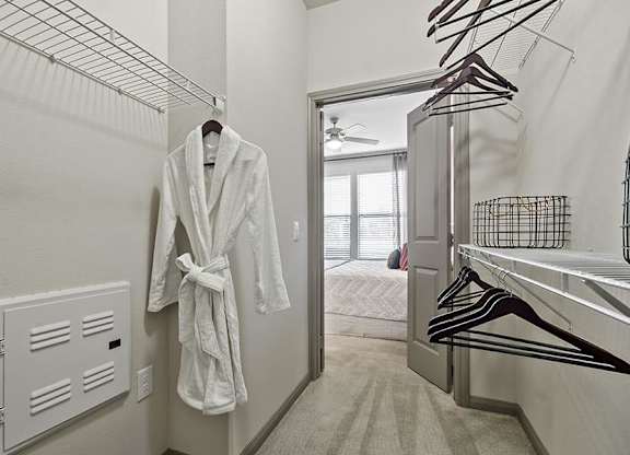 A white robe is hanging on a rack in a room.