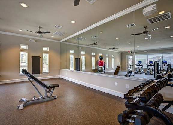 A gym with a mirror, weights, and exercise equipment.