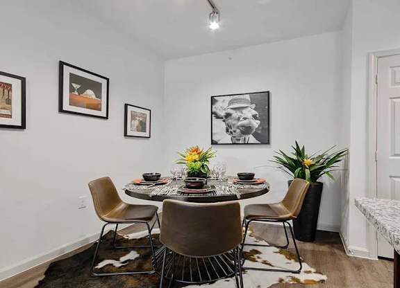 A dining room with a table set for four and a cowhide rug.