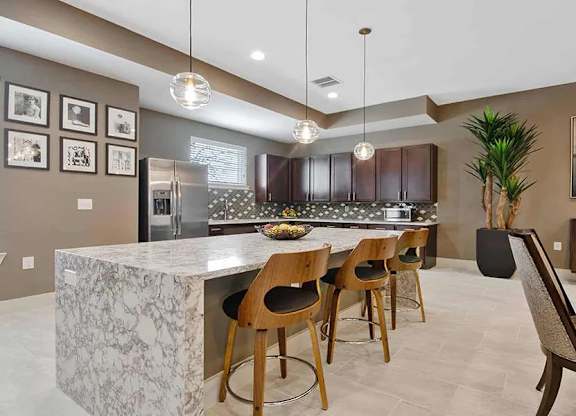 A kitchen with a marble island and wooden chairs.