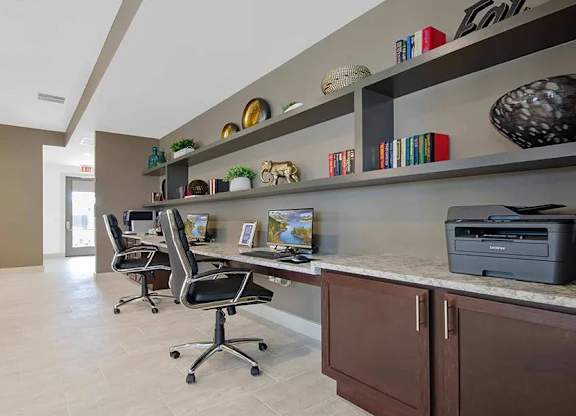 A home office with a desk, chairs, and shelves with decorative items.