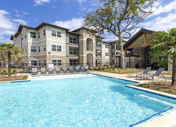 A large swimming pool in front of a multi-story residential building.