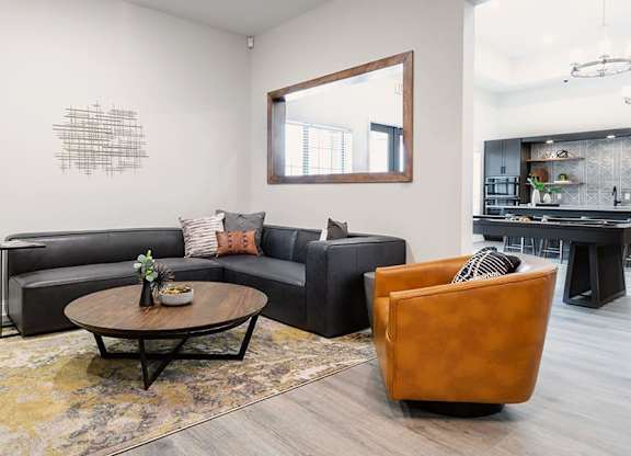 A living room with a black couch, a brown leather chair, and a coffee table with a vase of flowers on it.