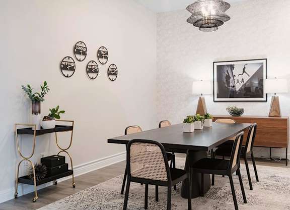 A dining room with a black table and chairs.