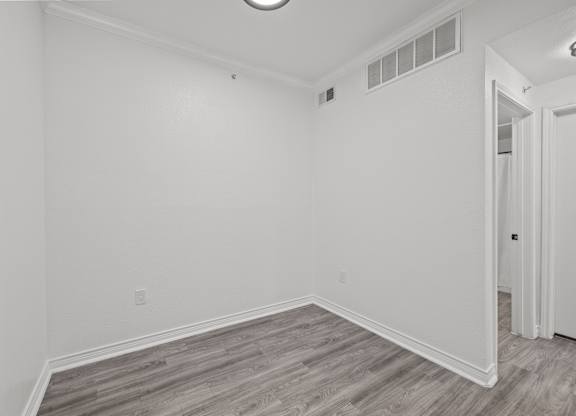 an empty room with white walls and wood flooring