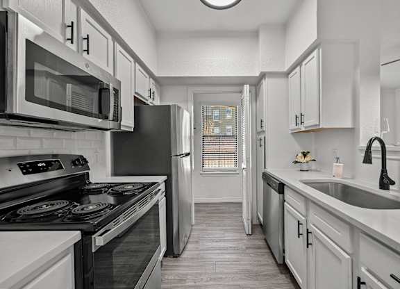 an empty kitchen with white cabinets and stainless steel appliances