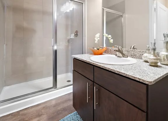 A modern bathroom with a sink, mirror, and shower.