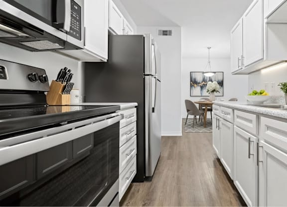 A modern kitchen with black and white appliances and wooden floors.