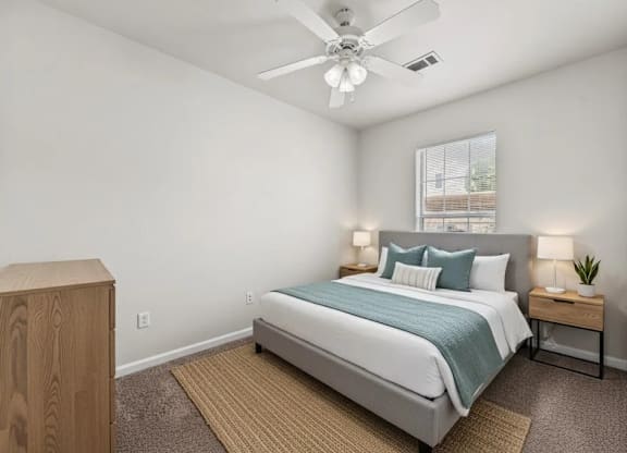A bedroom with a bed, nightstand, and a ceiling fan.