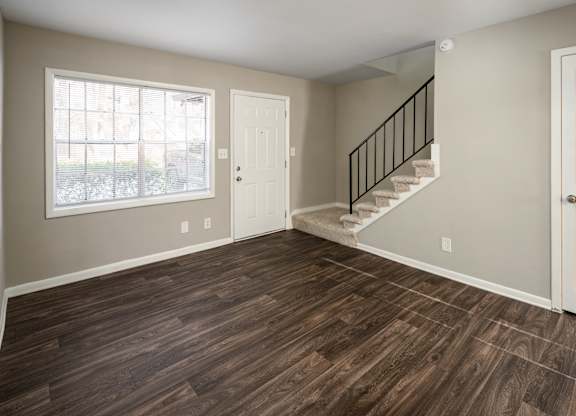 a bedroom with hardwood floors and a staircase