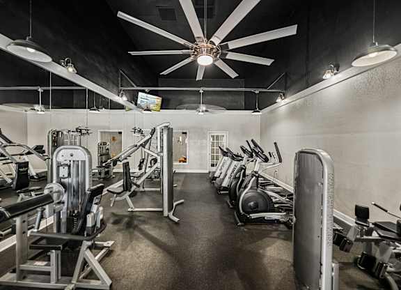 A gym with a variety of equipment including weights and cardio machines.