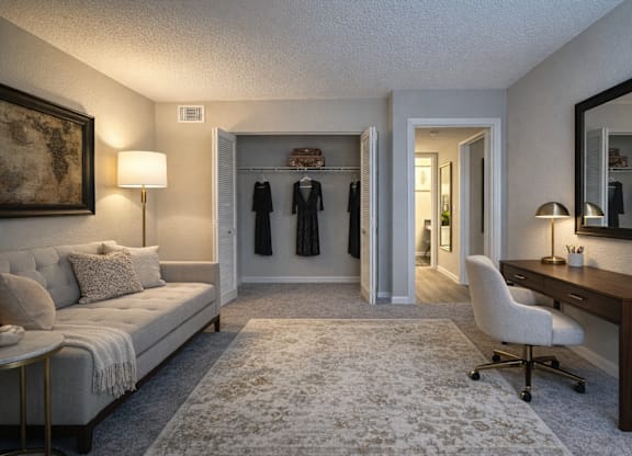 A well-lit room with a couch, desk, and a mirror.